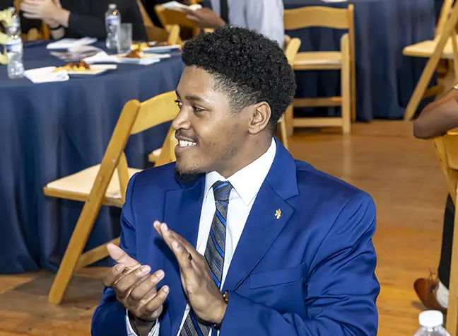 MSSI member wearing a blue suit and applauding.