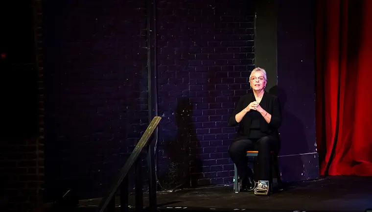 An ASL interpreter sits at the far-left end of the stage.