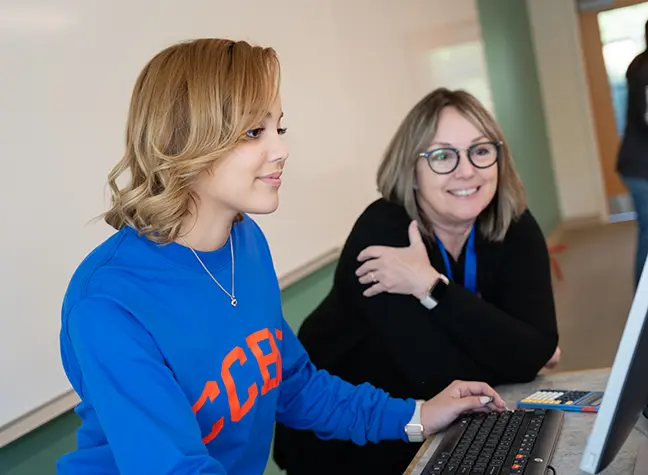 Academic advisor helps student on the computer.