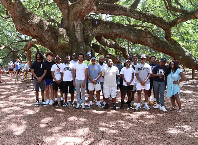 MSSI students with CCBC faculty trip directors under large tree.